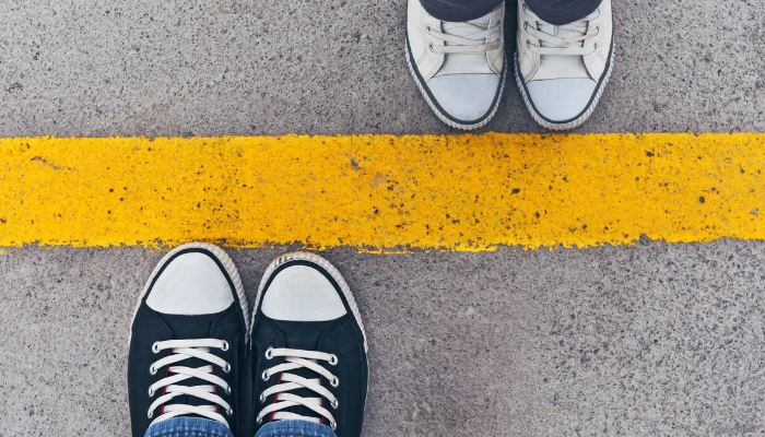 Top view of two pairs of sneakers standing on opposite sides of a yellow dividing line